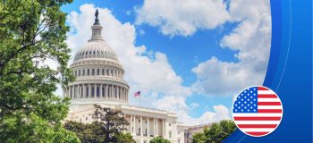 The White House (a large building with a towering dome structure, made of white stone) under a blue sky with clouds. Framed by trees (and an illustrated American flag graphic).